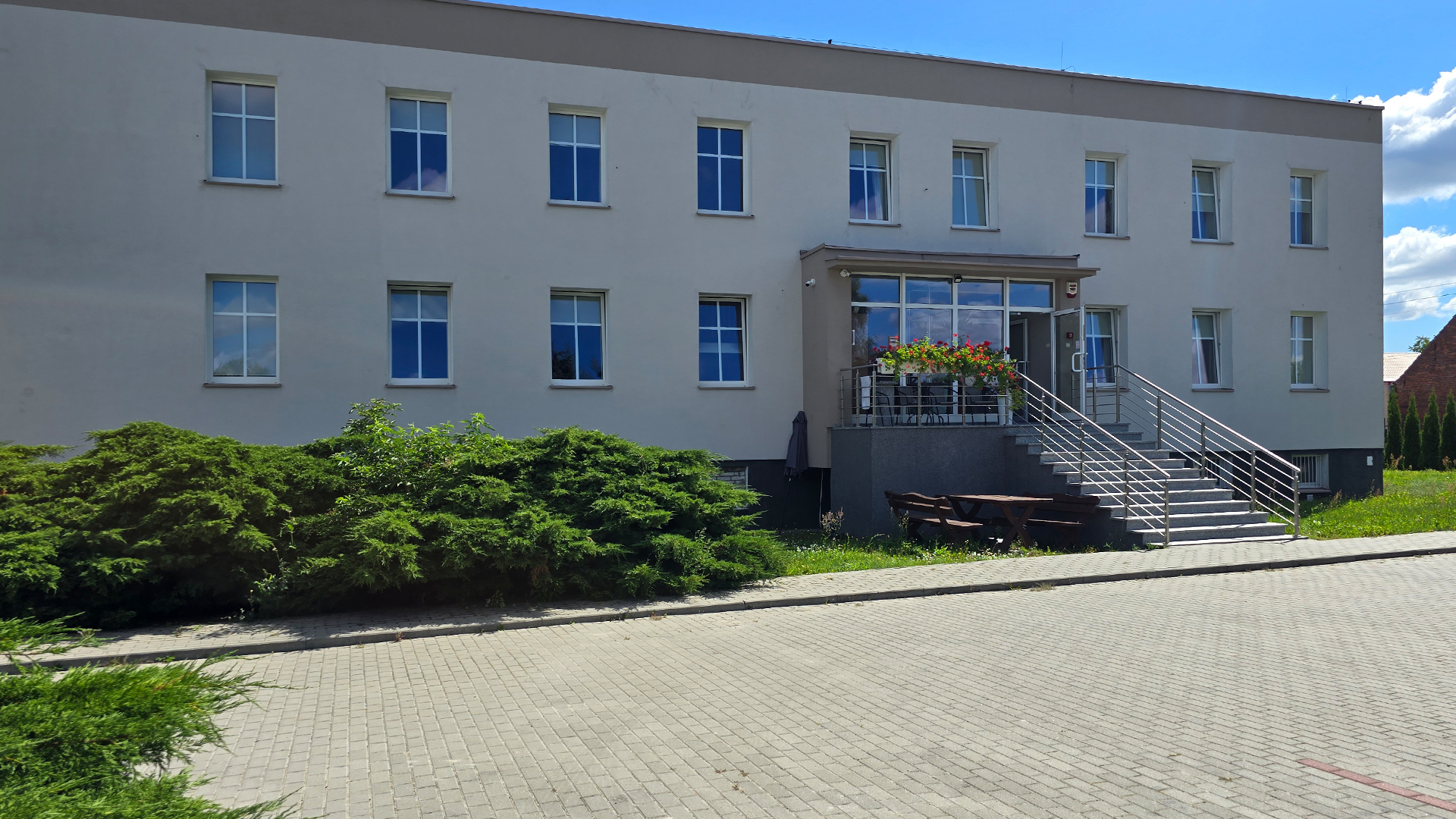 Front budynku noclegowego z wejściem, szerokimi schodami i ozdobnymi kwiatami na balkonie – Noclegi Gorzów w Baczynie