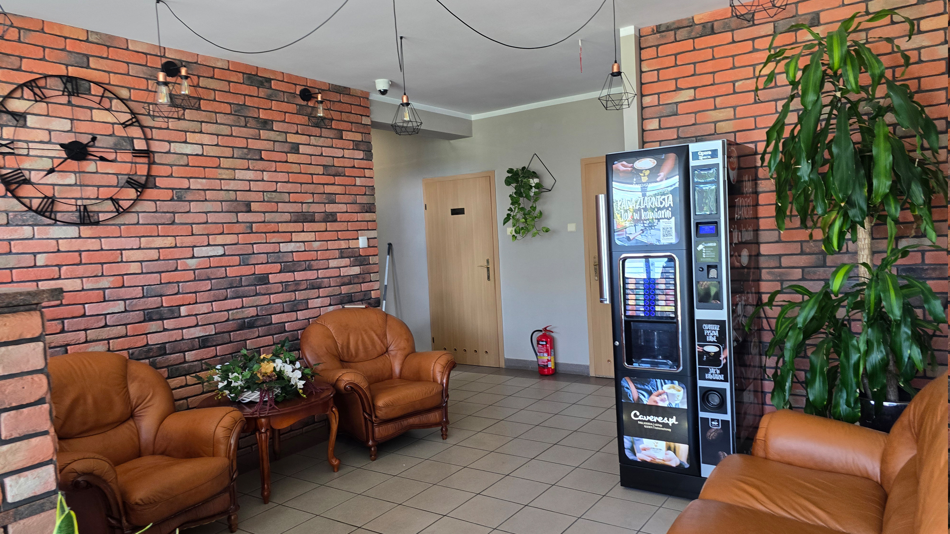 Recepcja z fotelami, automatem do kawy i czerwoną ceglaną ścianą – Noclegi Gorzów w Baczynie